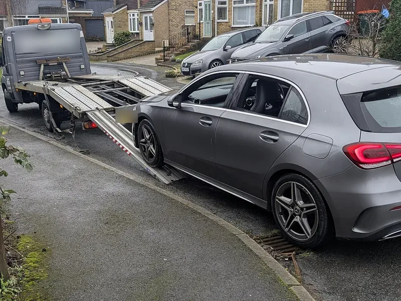Scrap car being loaded onto a recovery flatbed